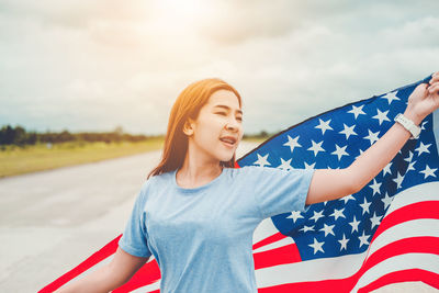 Young woman holding american flag on road
