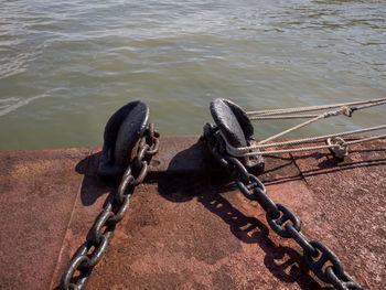 Close-up of rope tied to metal chain on lake