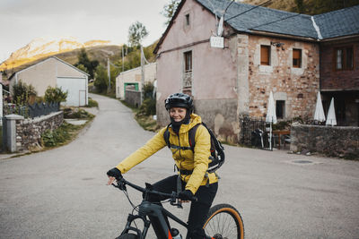 Portrait of boy riding bicycle by building