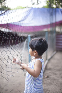 Boy standing by chainlink fence