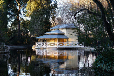 Built structure by lake against trees and plants