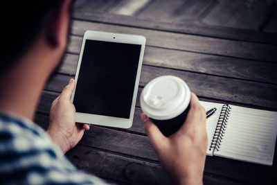 Man with disposable cup using digital tablet outdoors