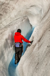 Rear view of man walking amidst glacier