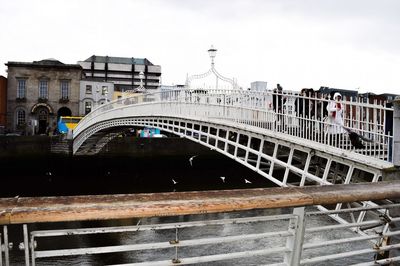 Bridge over river in city against sky