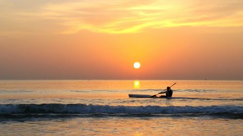 Silhouette of people on beach at sunset