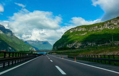 Empty road leading to mountains against sky