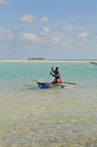 Man rowing boat in sea against sky