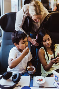 Girl showing camera to mother and brother while traveling in train