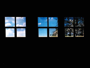 Silhouette trees against sky seen through glass window