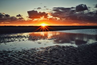 Sun shining through clouds over sea