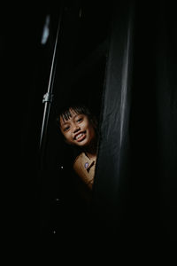 Portrait of girl smiling while standing in darkroom