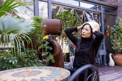 Portrait of young woman sitting against plants