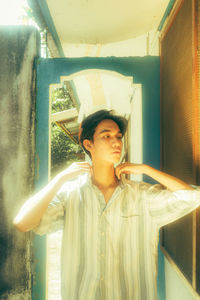 Portrait of young man standing against wall