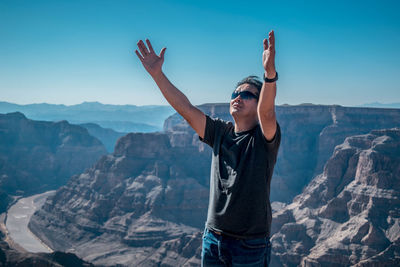 Man wearing sunglasses standing on mountain against sky