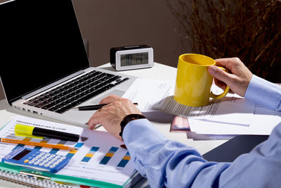 Midsection of businessman using laptop on table