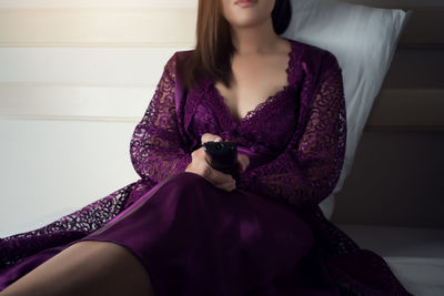 Midsection of woman in nightwear sitting at home