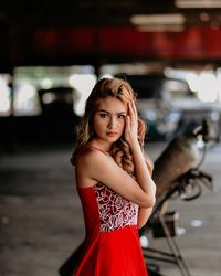 Portrait of beautiful young woman against red blurred background