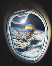 View of hot air balloon against sky seen through airplane window