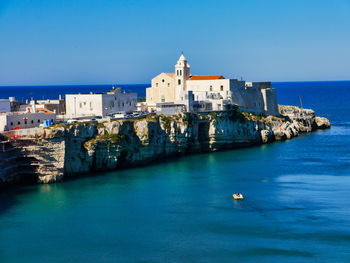 Buildings in sea against blue sky