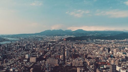 Aerial view of city against cloudy sky