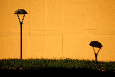 Street light on field against orange sky