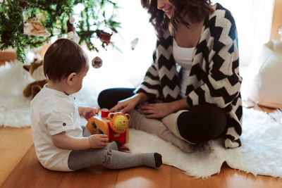 Rear view of mother and daughter sitting on toy at home