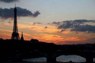 Tower bridge over cityscape against sky during sunset