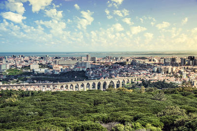 Aerial view of city by sea against cloudy sky