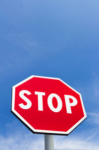 Low angle view of stop sign against blue sky