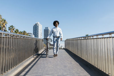 Mid adult man pushing his bicycle on a bridge in the city