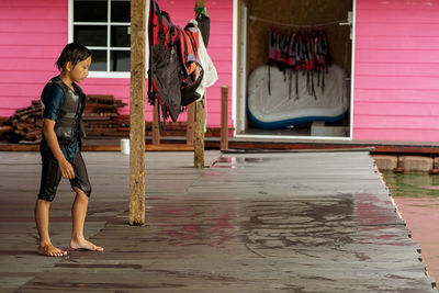 Side view of girl walking with life jacket on floor by lake