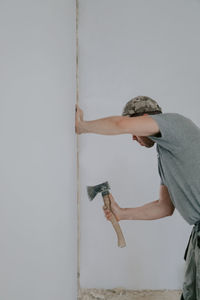 A young caucasian male builder clears a doorway using a crowbar.