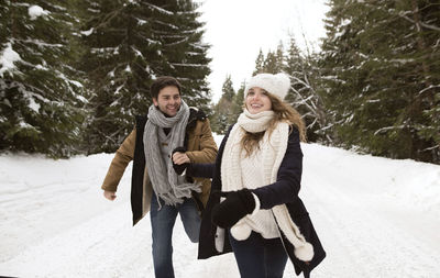 Happy young couple running in snow-covered winter landscape