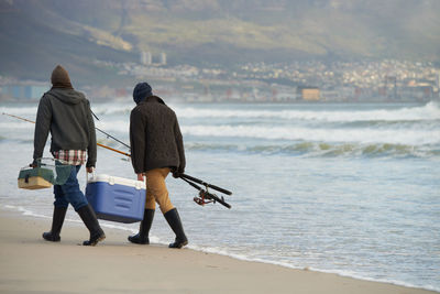 Rear view of people walking at beach