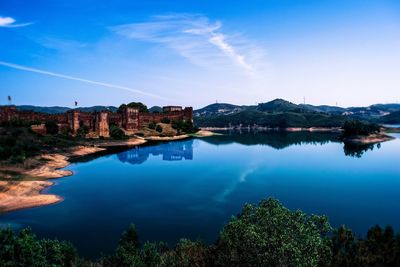 Scenic view of lake by trees against blue sky