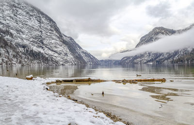 Scenic view of frozen lake by snowcapped mountains against sky