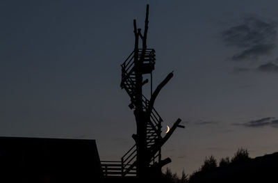 Low angle view of silhouette communications tower against sky at night