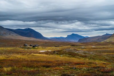 Scenic view of grassy field and mountains against cloudy sky