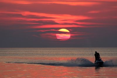 Man riding jet boat on sea against sky during sunset