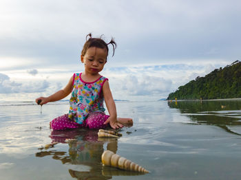 Cute girl in water against sky