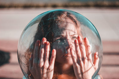 Close-up of thoughtful young woman wearing glass helmet in head during sunny day