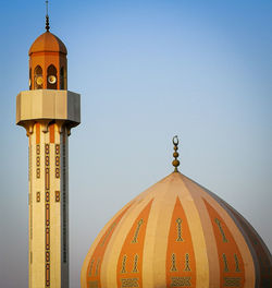 Low angle view of clock tower amidst buildings against clear sky