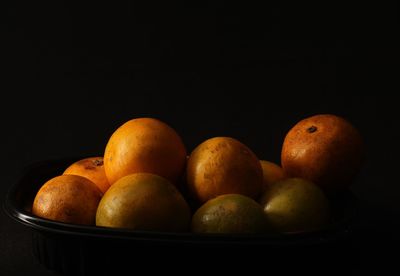 Close-up of fruits in bowl against black background