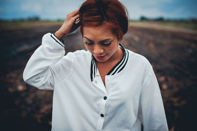 Young woman looking down while standing on field