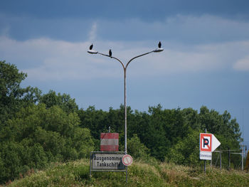 Road sign by street against sky