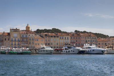 Boats in sea by city against sky