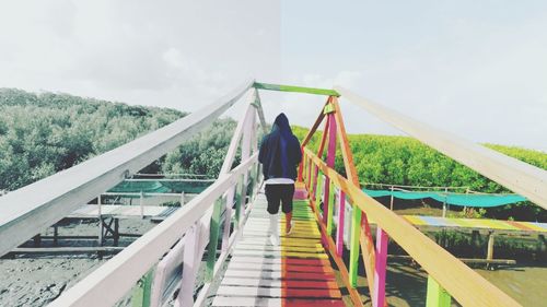 Rear view of woman walking on footbridge