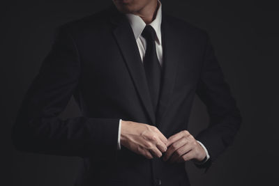 Midsection of man wearing mask against black background