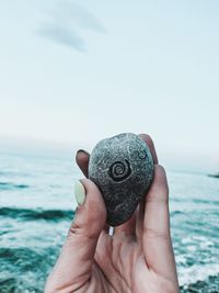 Close-up of hand holding sea against sky