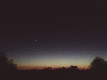 Silhouette of trees on landscape at sunset